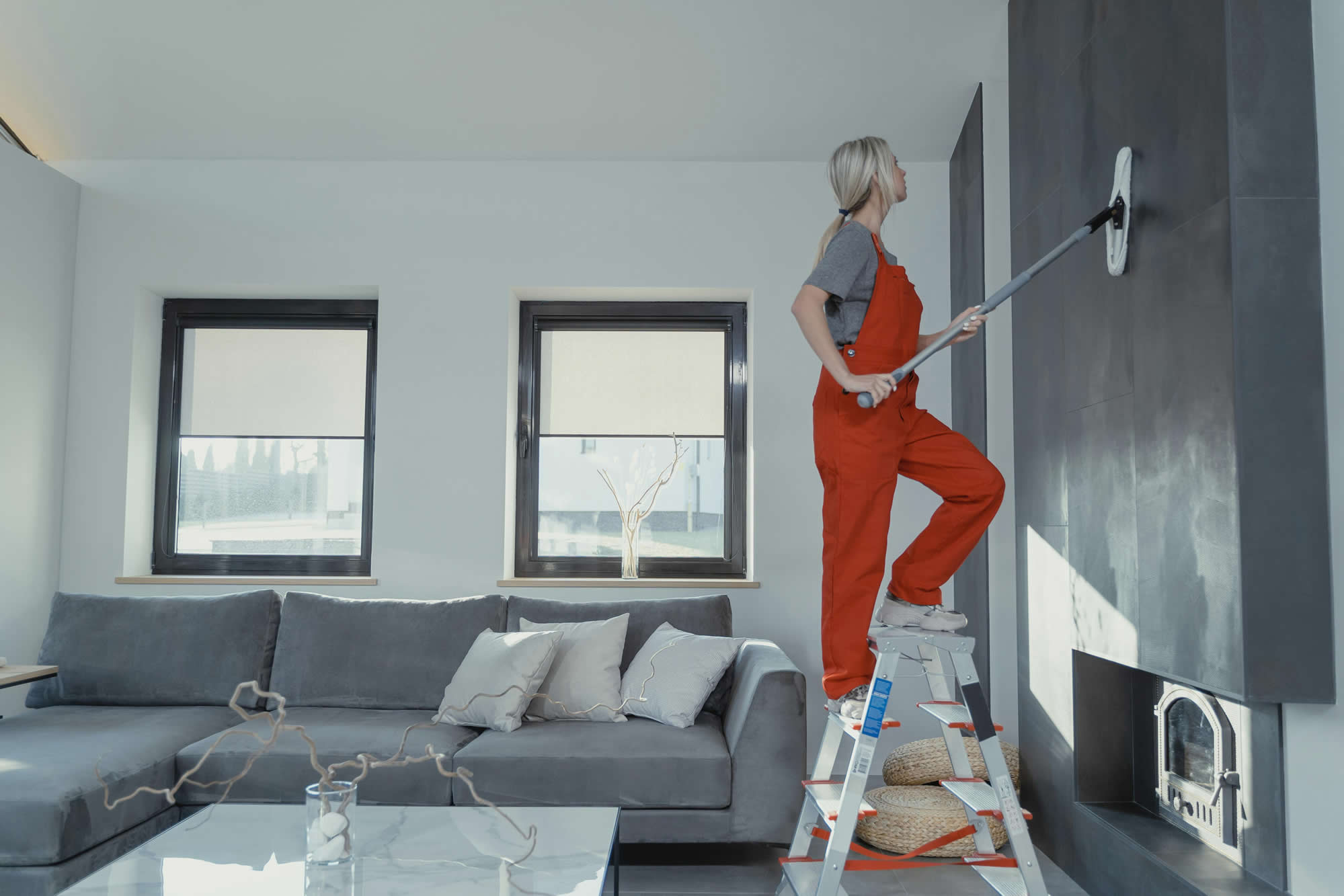 Professional cleaner on a stepladder cleaning a living room wall for house cleaning in Devonport